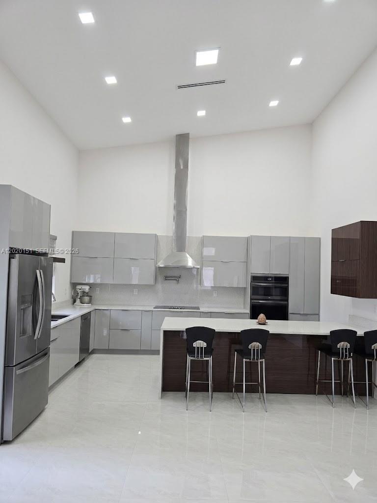A modern kitchen features gray cabinetry, a dark wood island, and stainless steel appliances — 19860 Skyhawk Ln, Loxahatchee FL 33470, LOXAHATCHEE, FL