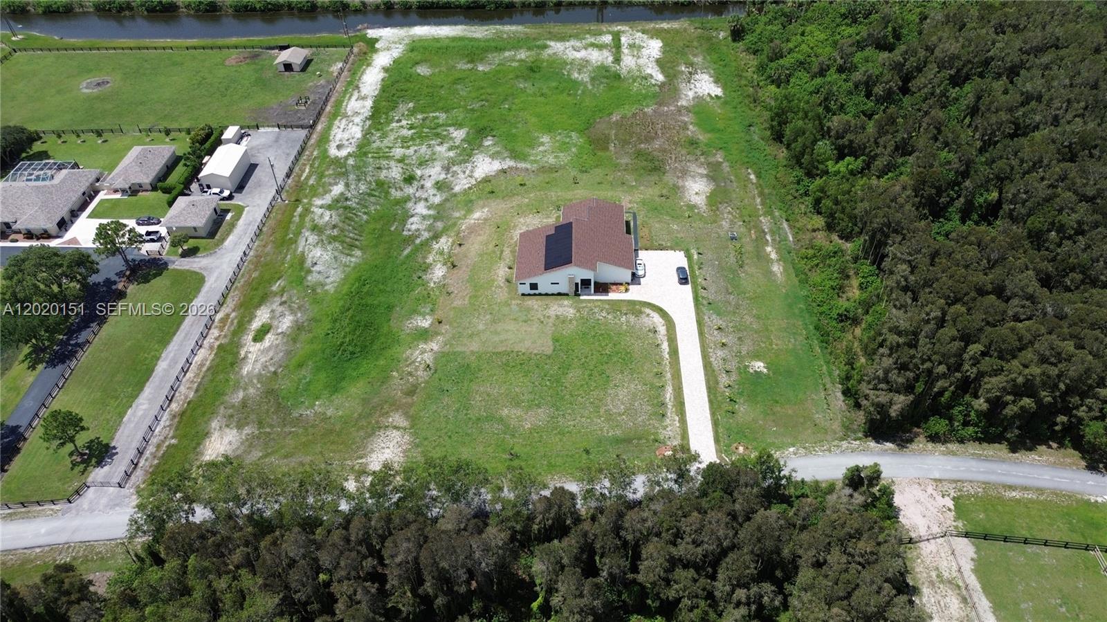 An aerial view shows a house with solar panels on a large, partially cleared lot — 19860 Skyhawk Ln, Loxahatchee FL 33470, LOXAHATCHEE, FL