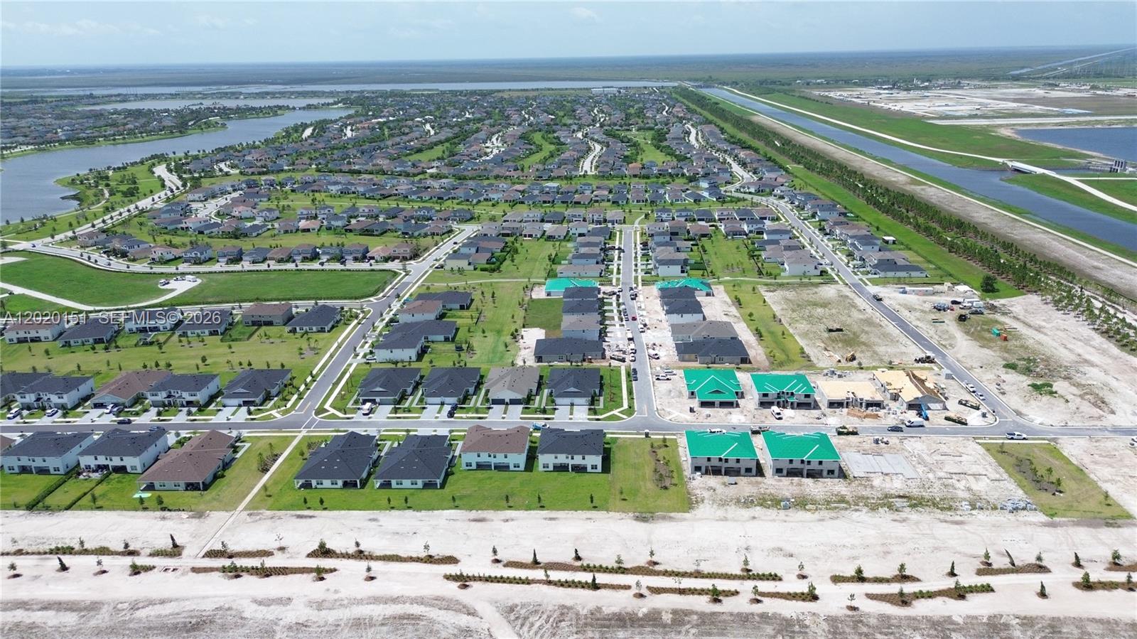 An aerial view shows a suburban residential neighborhood with houses, construction sites, and canals — 19860 Skyhawk Ln, Loxahatchee FL 33470, LOXAHATCHEE, FL