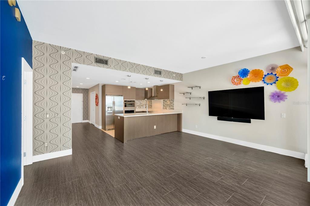 An open-concept living room and kitchen featuring dark wood-look tile flooring and decorative wall art — 145 2ND AVENUE S UNIT 521, ST PETERSBURG, FL