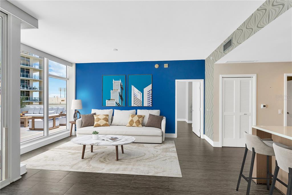 A living room features a blue accent wall, white sofa, marble coffee table, and balcony access — 145 2ND AVENUE S UNIT 521, ST PETERSBURG, FL