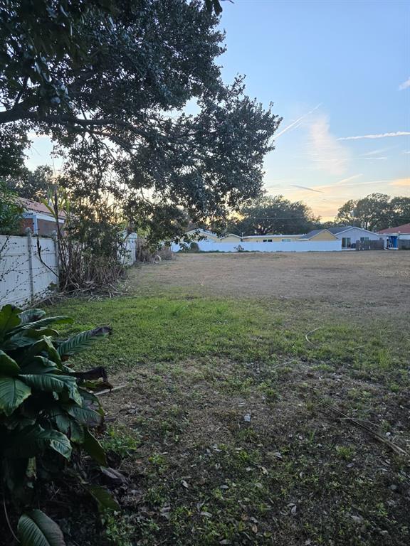 A large, flat, grassy vacant lot is bordered by a white fence and mature trees — 5625 ROSEMONT AVENUE, TAMPA, FL