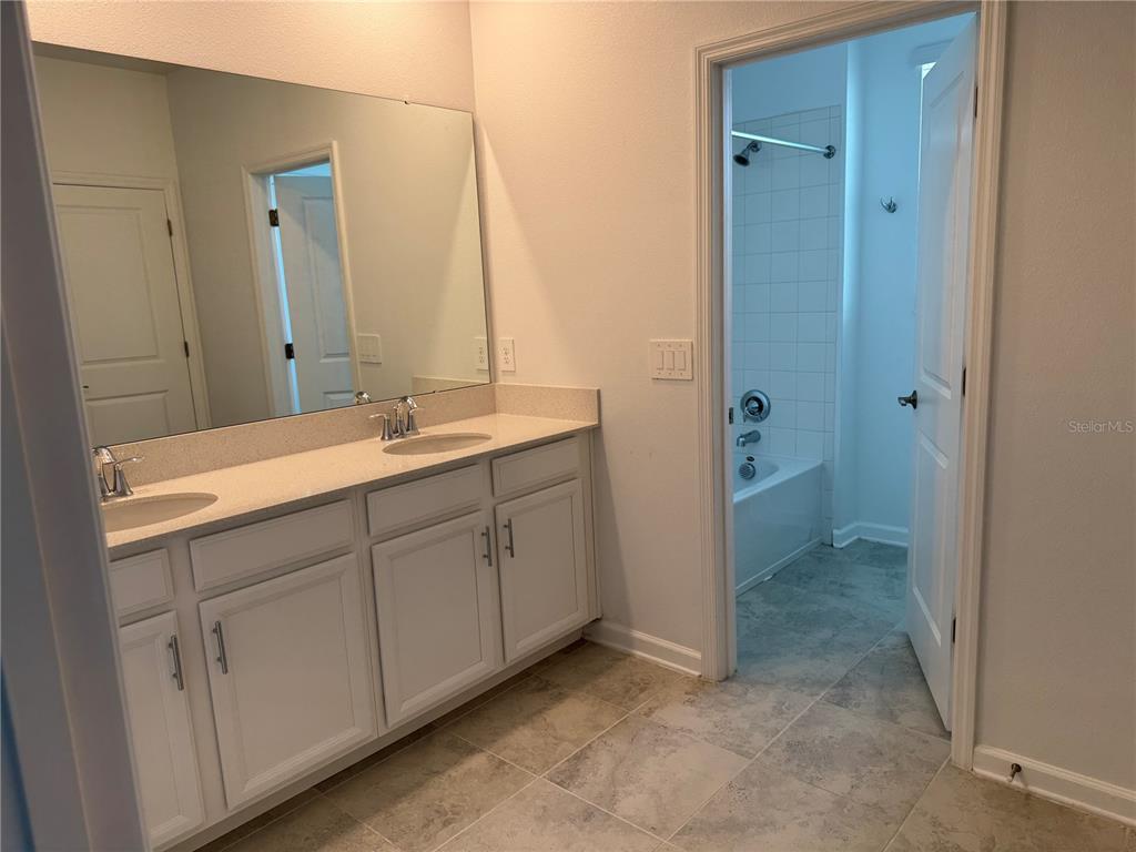 A bathroom features a double vanity with white cabinets, a large mirror, and tiled flooring — 1652 CROSS PRAIRIE PARKWAY, KISSIMMEE, FL