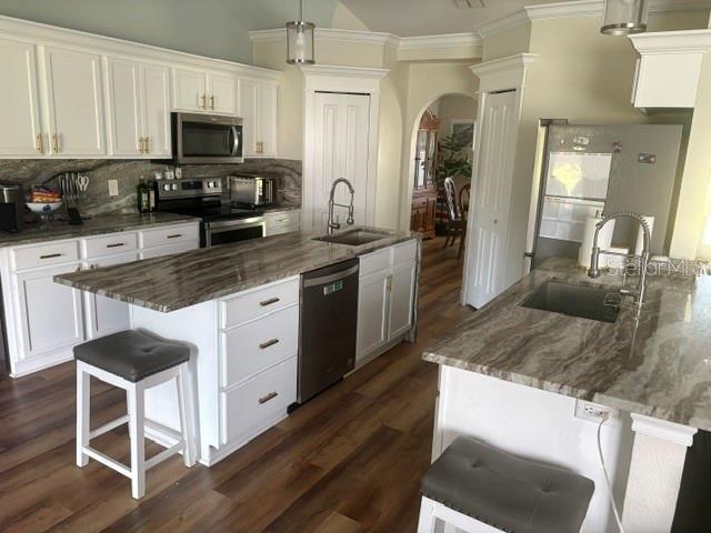 A kitchen features white cabinets, granite countertops, stainless steel appliances, and wood-look flooring — 6120 WATERFIELD WAY, ST CLOUD, FL