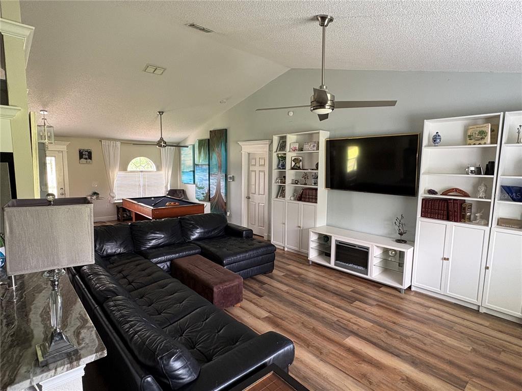 A living room features a black sectional sofa, a pool table, and white built-in shelving — 6120 WATERFIELD WAY, ST CLOUD, FL