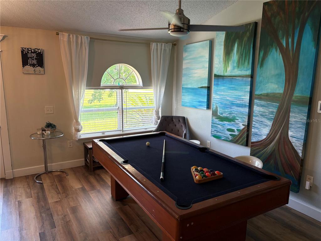 A game room features a pool table, wood-look flooring, and large landscape wall art — 6120 WATERFIELD WAY, ST CLOUD, FL