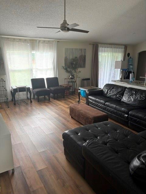 A living room features wood-look flooring, a black leather sofa, and a ceiling fan — 6120 WATERFIELD WAY, ST CLOUD, FL