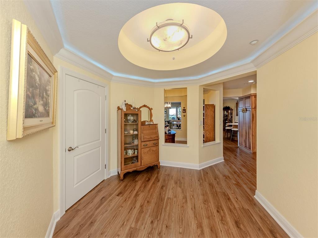 A foyer with wood-look flooring, a circular tray ceiling, and a view into a kitchen — 14021 BELLAGIO WAY UNIT 404, OSPREY, FL