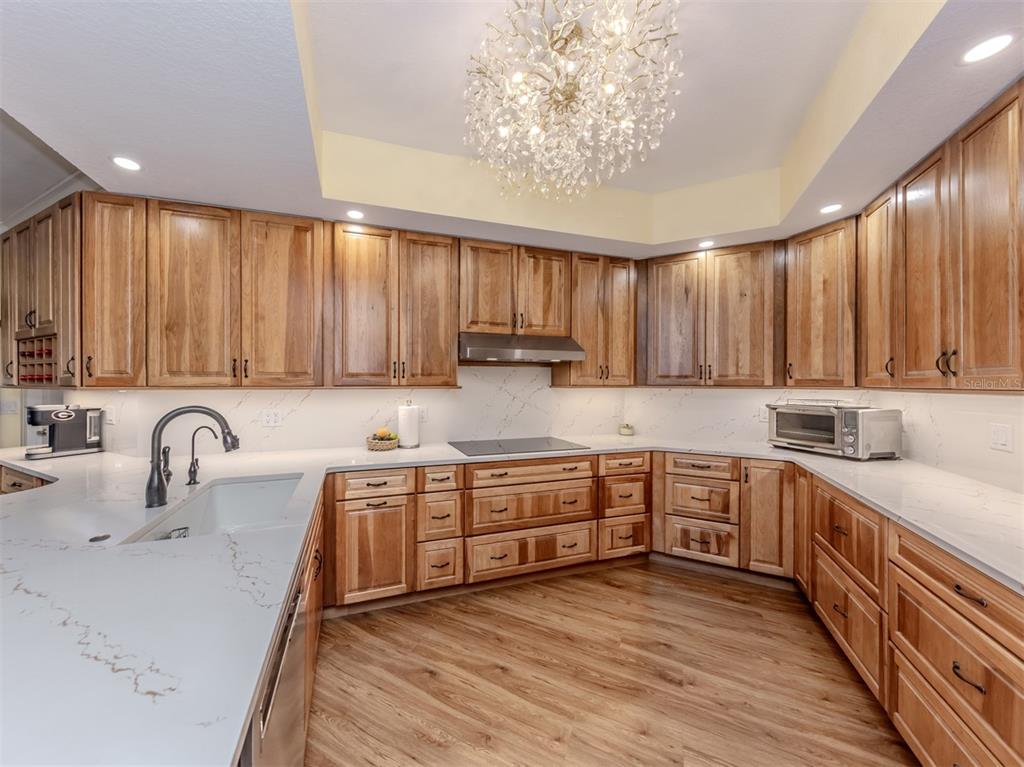 A spacious, empty living room with light yellow walls, wood-look flooring, and a balcony view — 14021 BELLAGIO WAY UNIT 404, OSPREY, FL