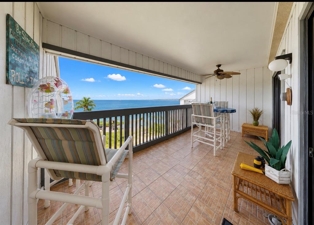 A covered balcony with tile flooring, patio furniture, and a view of the ocean — 810 BAHIA DEL SOL DRIVE UNIT 16, RUSKIN, FL