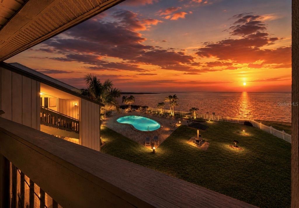 An elevated view of a swimming pool and lawn overlooking the ocean at sunset — 810 BAHIA DEL SOL DRIVE UNIT 16, RUSKIN, FL