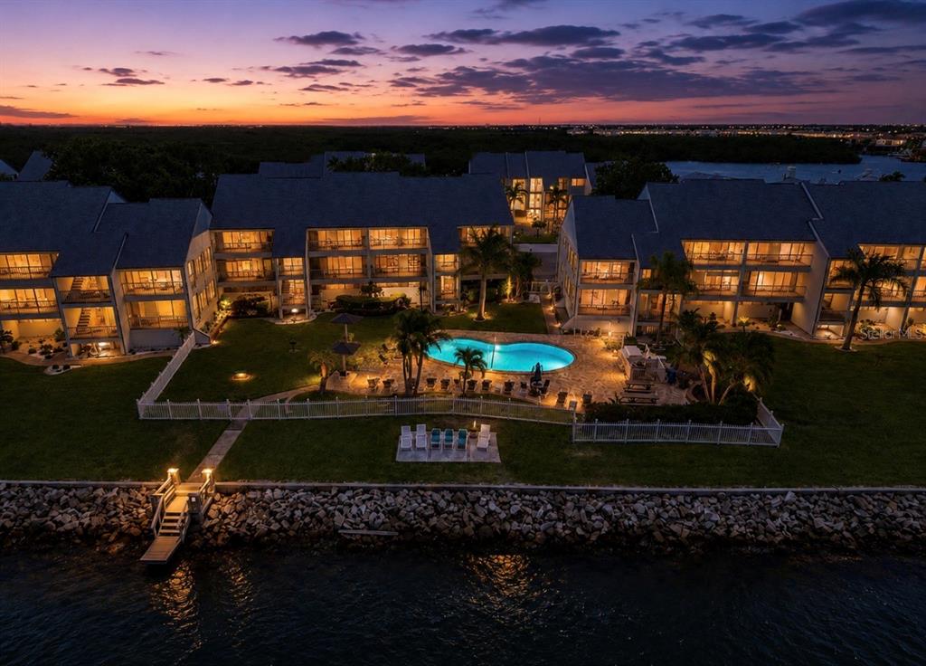 An aerial view of a multi-story apartment complex at dusk with a central swimming pool — 810 BAHIA DEL SOL DRIVE UNIT 16, RUSKIN, FL