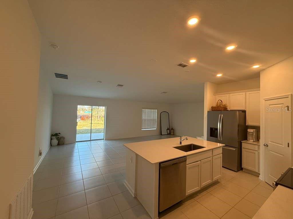 An open-concept kitchen with a center island overlooks a living area with tile flooring — 2359 POCKY WAY, KISSIMMEE, FL