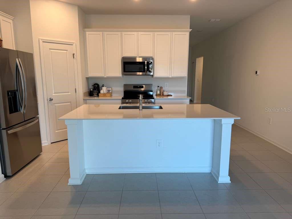 A kitchen features white cabinets, stainless steel appliances, and a large central island — 2359 POCKY WAY, KISSIMMEE, FL