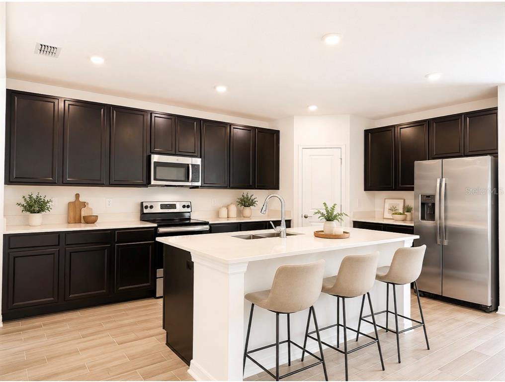 A kitchen with dark cabinets, white countertops, a central island, and stainless steel appliances — 924 SERCHIO STREET, HAINES CITY, FL