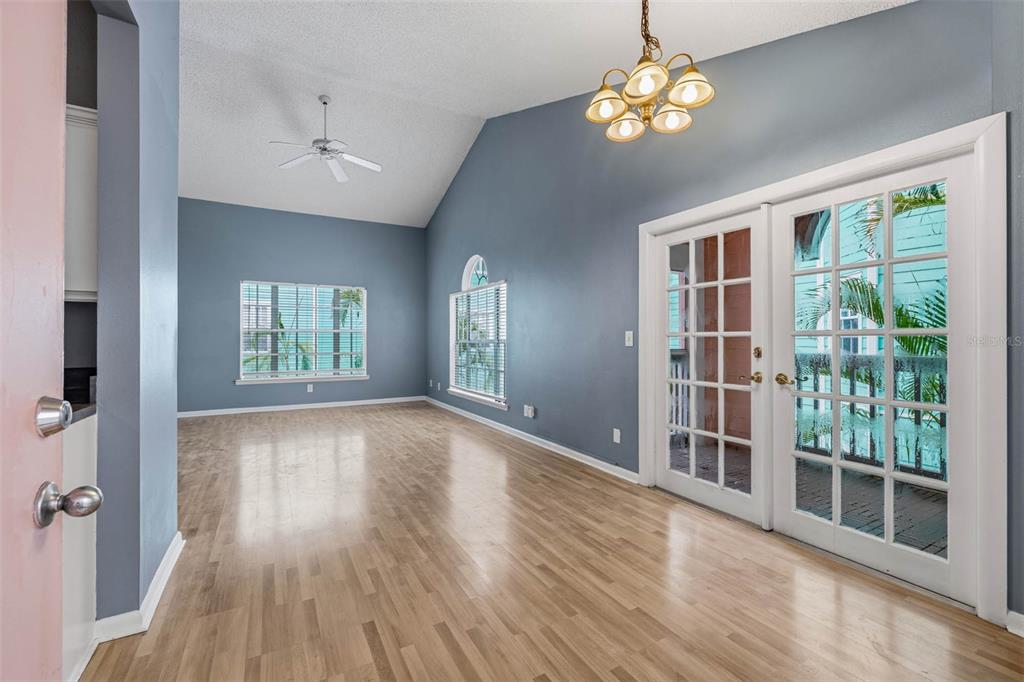 An empty room with blue walls, light wood floors, a vaulted ceiling, and French doors — 3002 W CLEVELAND STREET UNIT A8, TAMPA, FL
