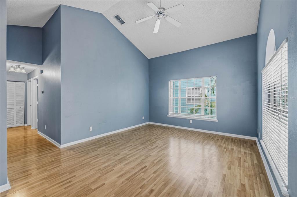 An empty room with blue walls, vaulted ceilings, a ceiling fan, and light wood flooring — 3002 W CLEVELAND STREET UNIT A8, TAMPA, FL