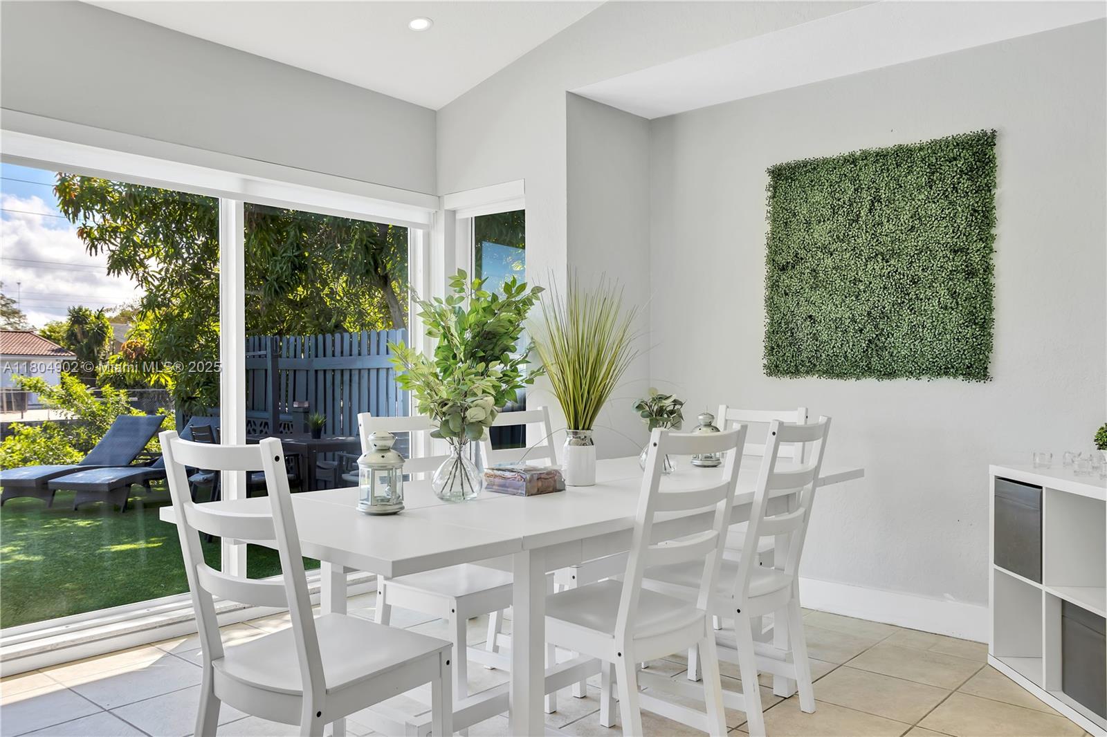 A dining room features a white table, chairs, and a wall-mounted artificial green plant panel — 2828 Cleveland St, Hollywood FL 33020, HOLLYWOOD, FL