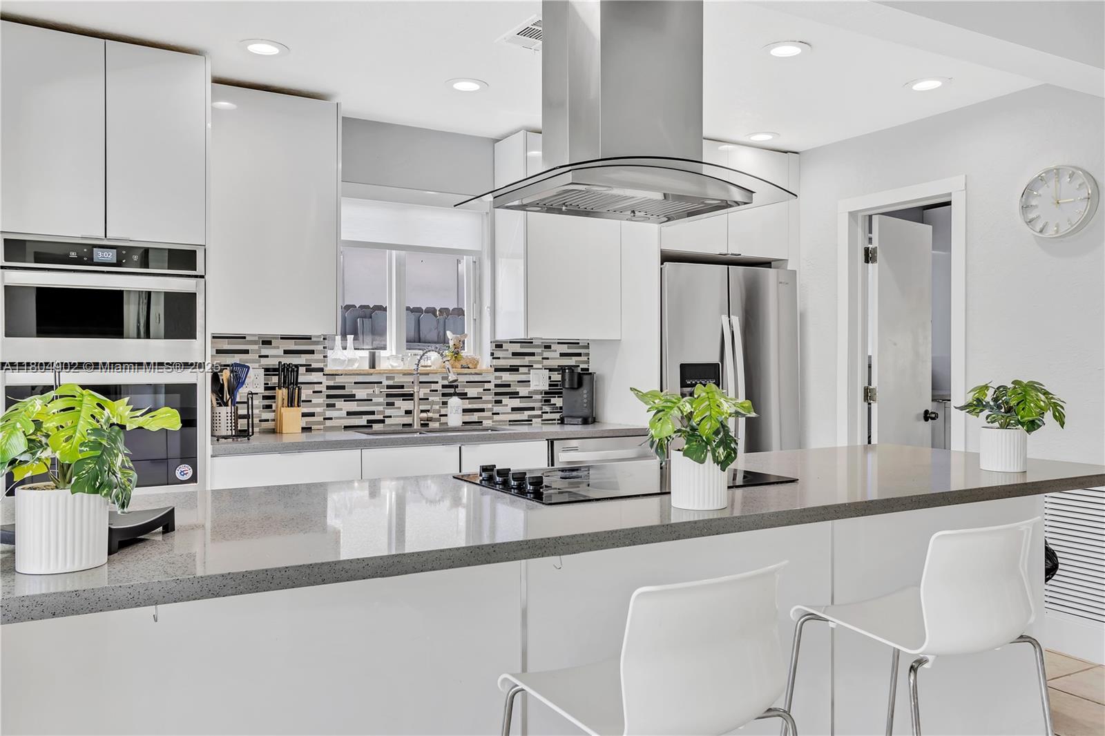A modern kitchen features white cabinetry, stainless steel appliances, a gray countertop, and a center island — 2828 Cleveland St, Hollywood FL 33020, HOLLYWOOD, FL