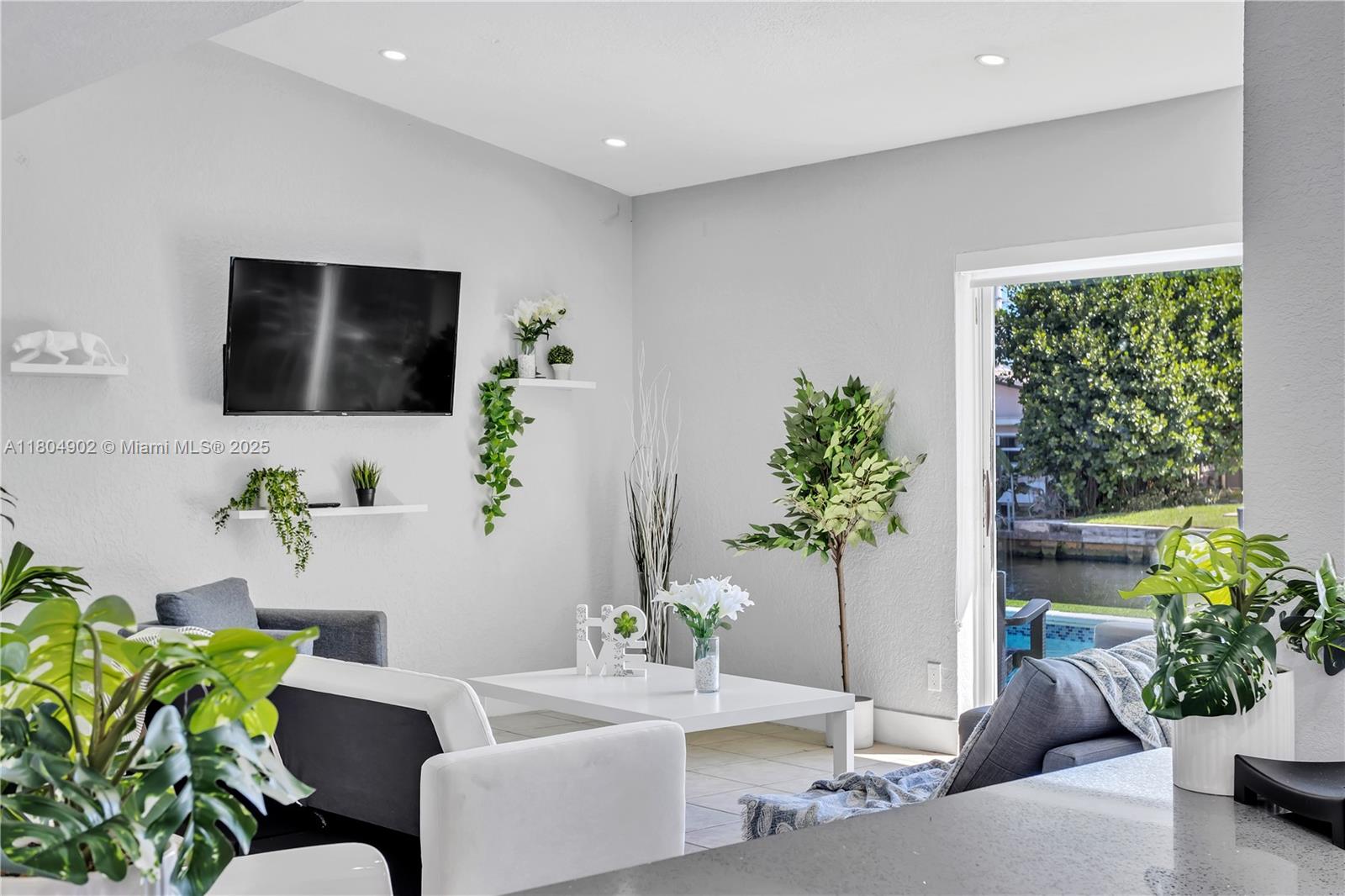 A living room features gray sofas, a white coffee table, and a view of a canal — 2828 Cleveland St, Hollywood FL 33020, HOLLYWOOD, FL