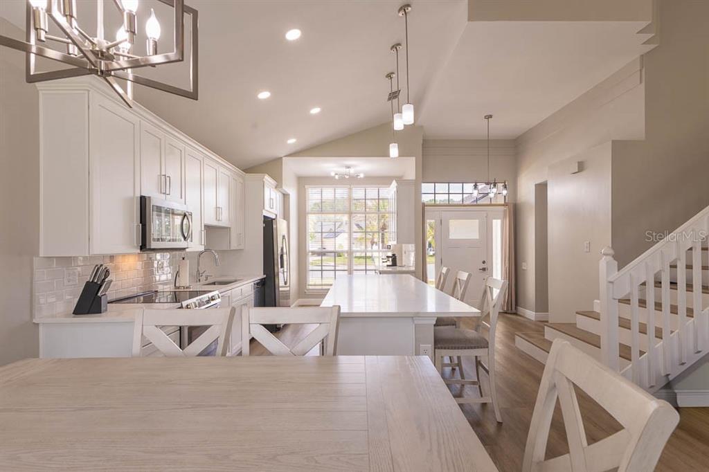 A bright kitchen features white cabinetry, a large center island, and a dining area — 3432 IDLEGROVE COURT, ORLANDO, FL