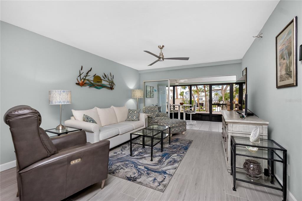 A living room features light gray flooring, a white sofa, a leather recliner, and sliding doors — 1501 BEACH ROAD UNIT 210, ENGLEWOOD, FL