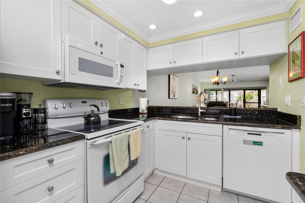 A kitchen with white cabinets, dark countertops, white appliances, and light green walls — 1501 BEACH ROAD UNIT 210, ENGLEWOOD, FL