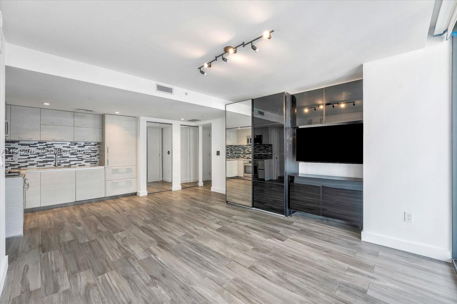 A modern open-concept living area features light wood-look flooring, a kitchen, and a dark media unit — 1300 S Miami Ave # 4807, Miami FL 33130, MIAMI, FL