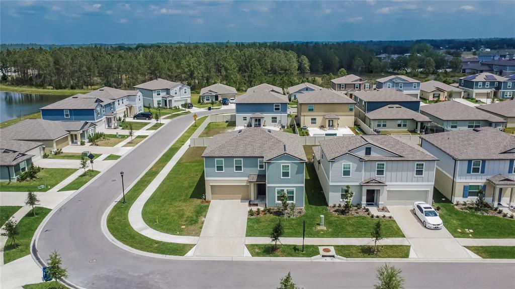 An aerial view of a suburban neighborhood featuring several two-story houses and a curved street — 34780 RAINVILLE LOOP, ZEPHYRHILLS, FL