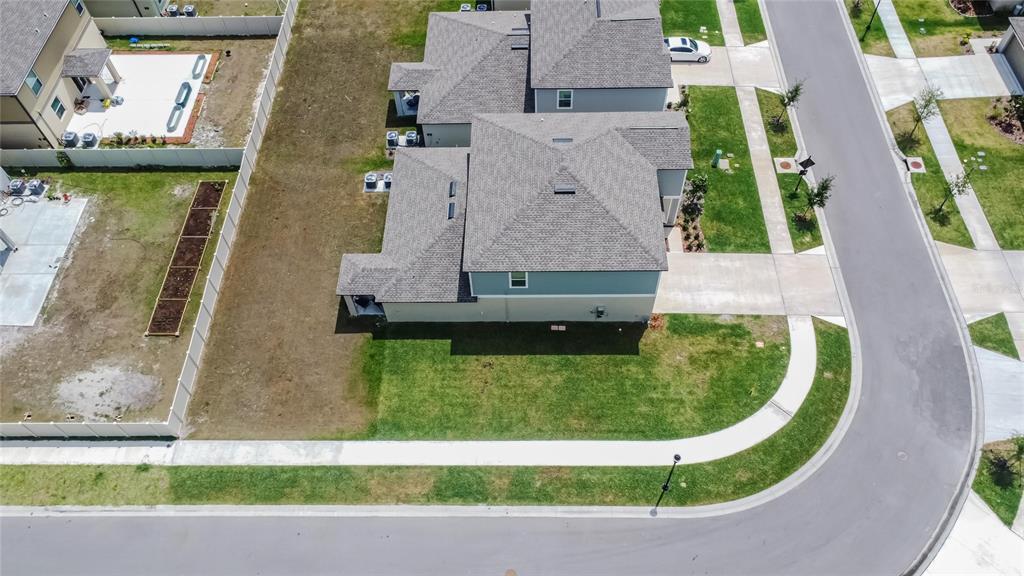 An aerial view shows a two-story house with a gray roof and a corner lot — 34780 RAINVILLE LOOP, ZEPHYRHILLS, FL