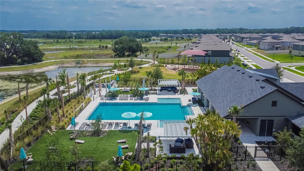 An aerial view of a community swimming pool, lounge area, and clubhouse in a residential neighborhood — 34780 RAINVILLE LOOP, ZEPHYRHILLS, FL