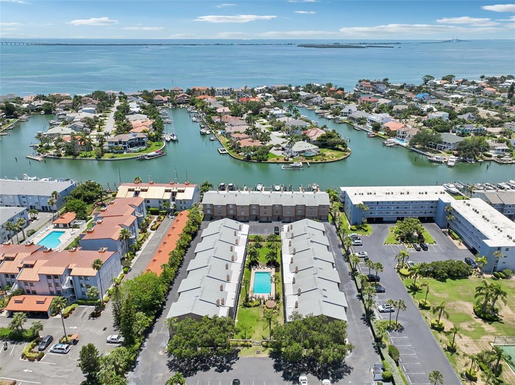 An aerial view shows waterfront townhomes, a swimming pool, and a marina on the bay — 637 PINELLAS BAYWAY UNIT 105, TIERRA VERDE, FL