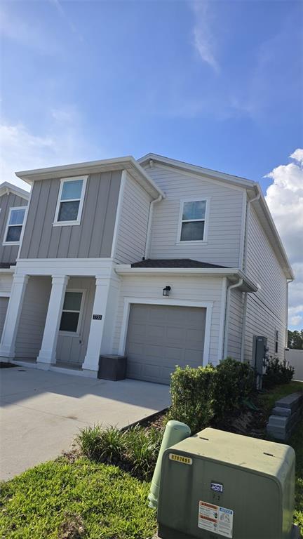 A two-story house exterior features light siding, a single-car garage, and a front porch — 7733 STONE CREEK TRAIL, KISSIMMEE, FL