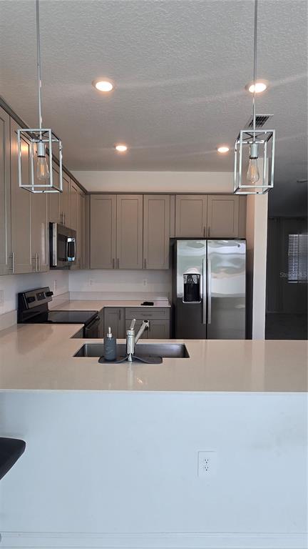A kitchen with grey cabinets, stainless steel appliances, and a quartz countertop island — 7733 STONE CREEK TRAIL, KISSIMMEE, FL