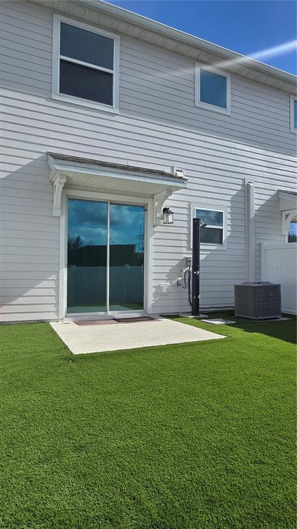 The exterior of a two-story house features white siding, a sliding glass door, and turf — 7733 STONE CREEK TRAIL, KISSIMMEE, FL
