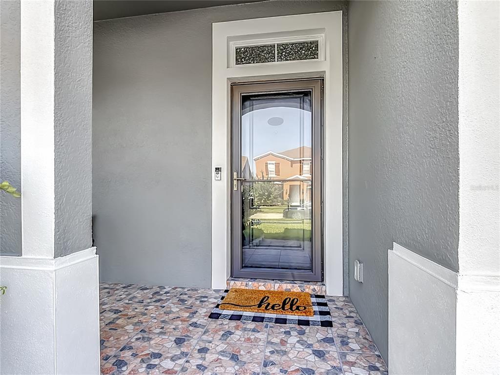 A front porch with tiled flooring, a storm door, and a hello welcome mat — 1553 CATERPILLAR STREET, ST CLOUD, FL