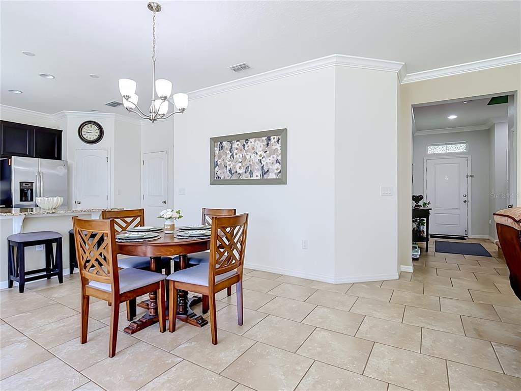 A dining area with a wooden table, chairs, and tile flooring adjacent to a kitchen — 1553 CATERPILLAR STREET, ST CLOUD, FL
