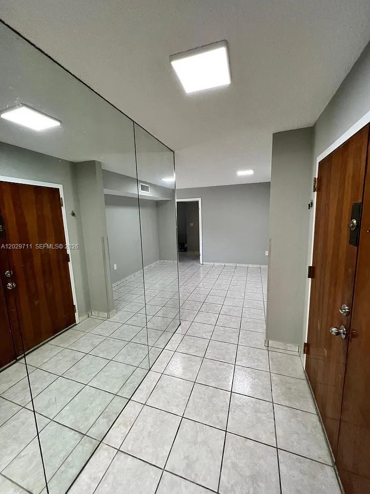 A tiled hallway features a large mirrored wall and two wooden doors — 1300 SW 122nd Ave # 2, Miami FL 33184, MIAMI, FL