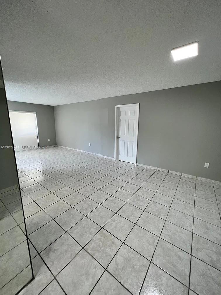 An empty room features gray walls, a white door, and light-colored tile flooring — 1300 SW 122nd Ave # 2, Miami FL 33184, MIAMI, FL