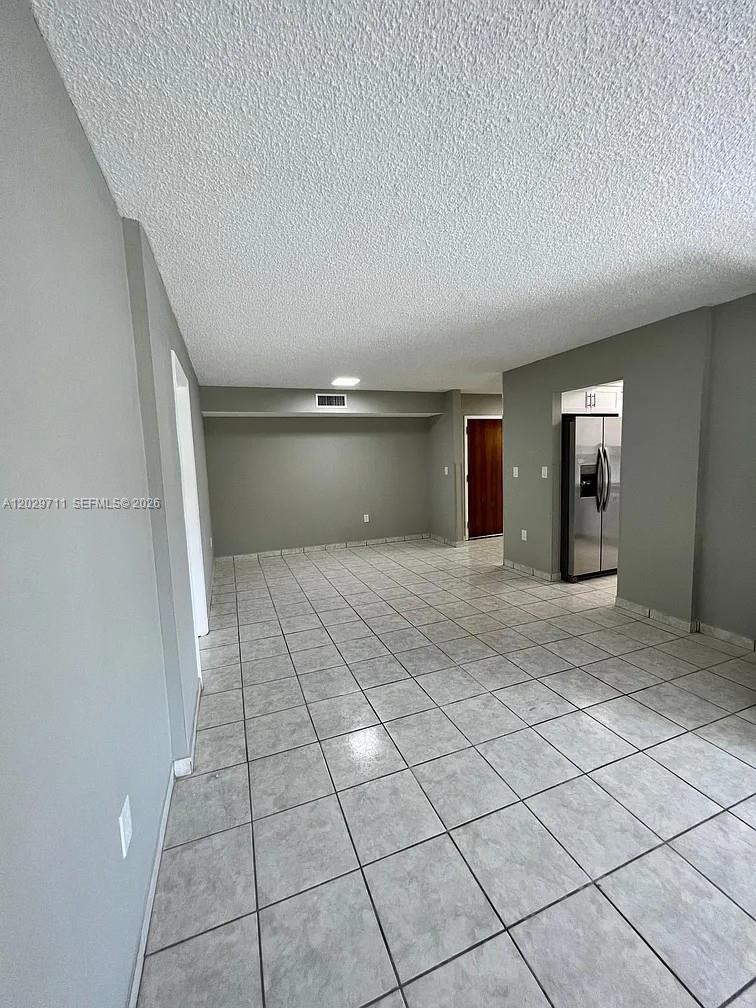 An empty room features gray walls, a textured ceiling, and light-colored square floor tiles — 1300 SW 122nd Ave # 2, Miami FL 33184, MIAMI, FL