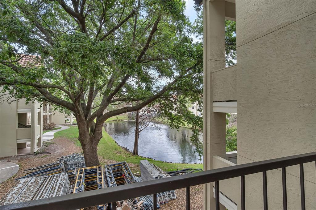 A balcony view overlooking a pond, a large tree, and construction materials on the ground — 3016 PARKWAY BOULEVARD UNIT 206, KISSIMMEE, FL