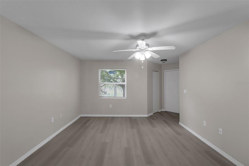 An empty room features light gray walls, wood-look flooring, a ceiling fan, and a window — 3016 PARKWAY BOULEVARD UNIT 206, KISSIMMEE, FL