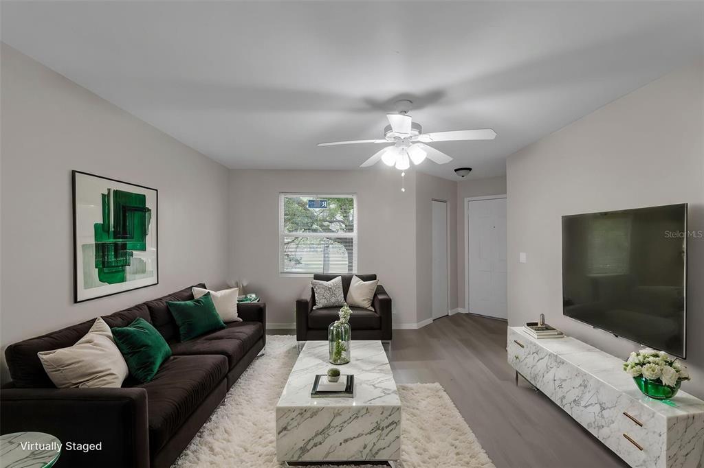 A living room features a dark sofa, marble coffee table, television, and white ceiling fan — 3016 PARKWAY BOULEVARD UNIT 206, KISSIMMEE, FL