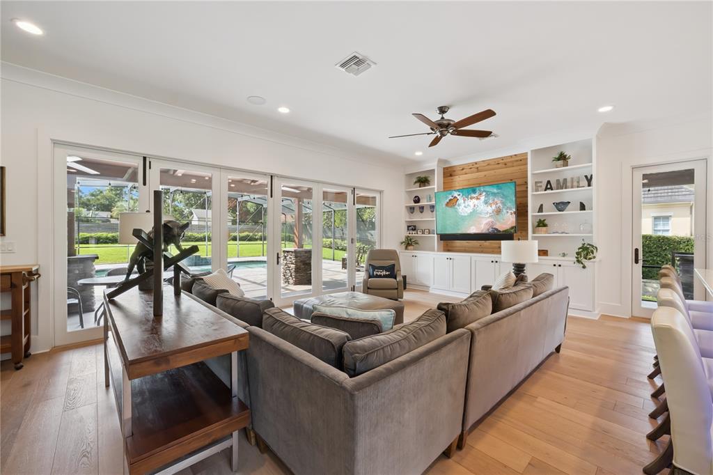 A living room features a large sectional sofa, built-in shelving, and sliding glass doors to a pool — 11539 LAKE BUTLER BOULEVARD, WINDERMERE, FL