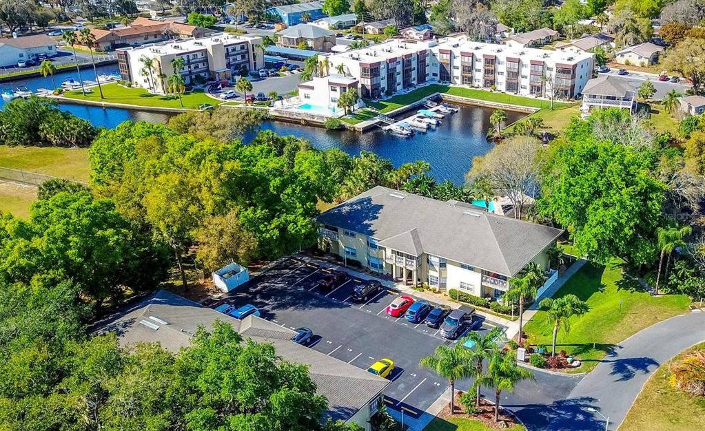 An aerial view shows a multi-story apartment building with a parking lot and canal — 5551 EXECUTIVE DRIVE, NEW PORT RICHEY, FL