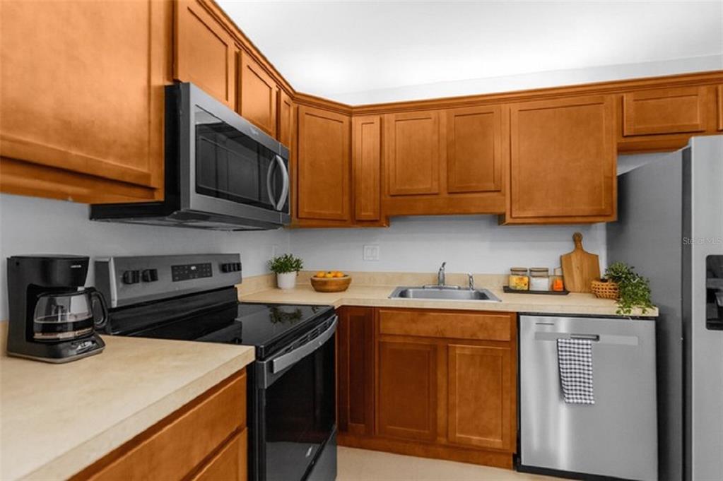 A kitchen features wood cabinets, stainless steel appliances, and light-colored countertops — 5551 EXECUTIVE DRIVE, NEW PORT RICHEY, FL