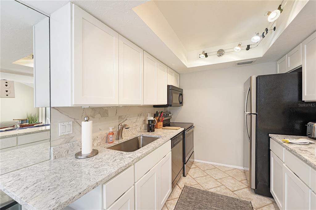 A kitchen features white cabinets, granite countertops, stainless steel appliances, and a tiled floor — 5903 W 43RD ST. W. UNIT 5903, BRADENTON, FL
