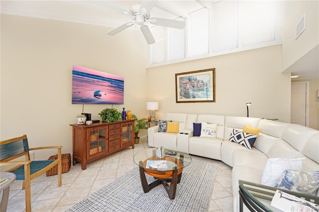 A living room features a white sectional sofa, a wooden media console, and vaulted ceilings — 5903 W 43RD ST. W. UNIT 5903, BRADENTON, FL