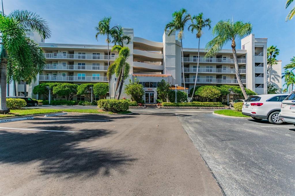 A multi-story apartment building with balconies and palm trees sits behind a paved parking lot — 5901 BAHIA DEL MAR CIRCLE UNIT 422, ST PETERSBURG, FL