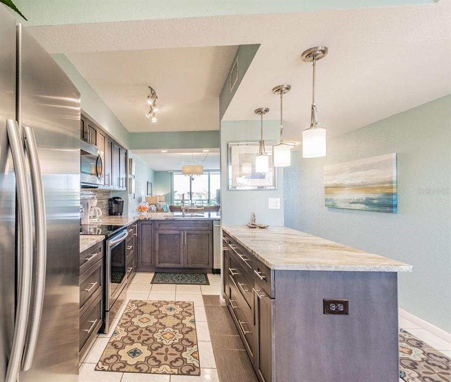 A kitchen features dark wood cabinets, a stone-topped island, and pendant lighting — 5901 BAHIA DEL MAR CIRCLE UNIT 422, ST PETERSBURG, FL
